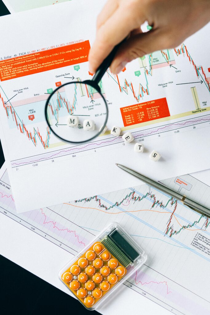 pexels-photo-6120177-6120177 Magnifying glass focusing on market data and charts indicating financial analysis concept.